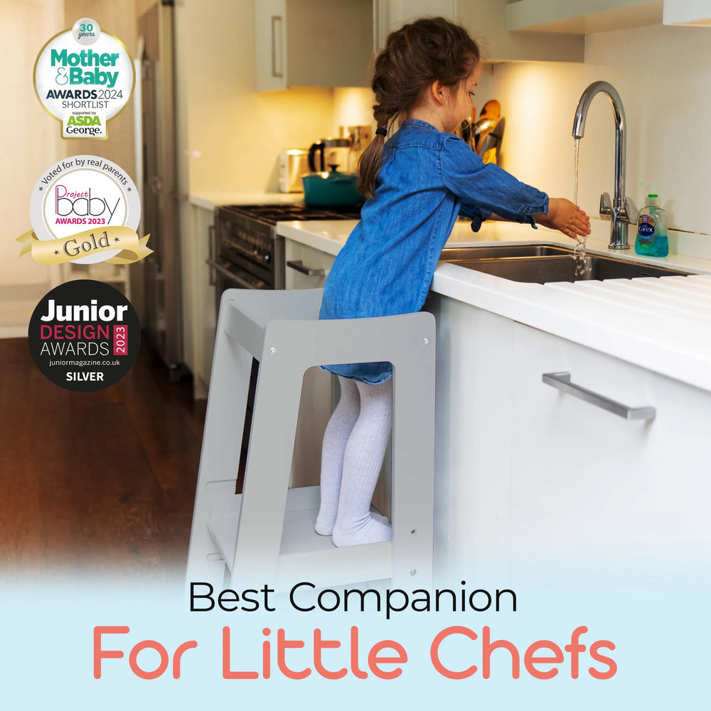 grey adjustable toddler tower positioned at kitchen sink for easy reach with awards